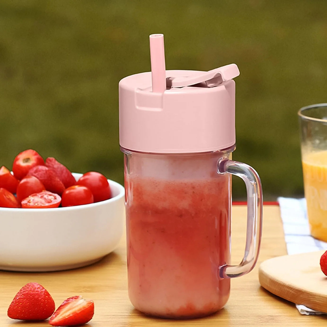 Portable mini blender bottle in mint and pink colors with fresh fruit inside